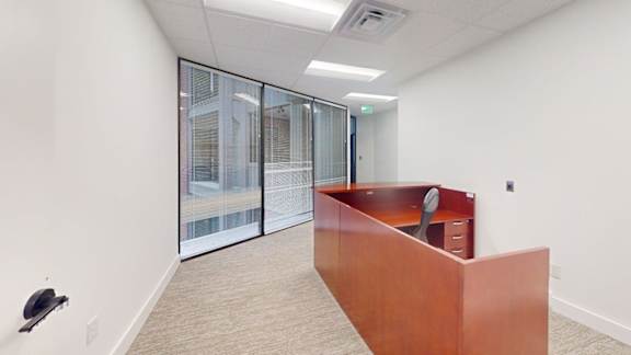 A room with a brown desk and a window with blinds.