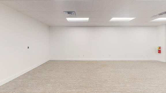 A large empty room with a carpeted floor and white walls.