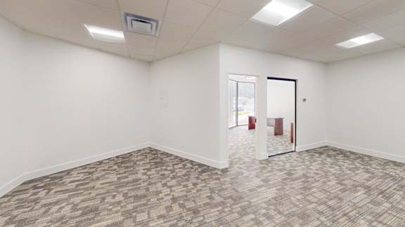 A room with a carpeted floor and a door on the right side.
