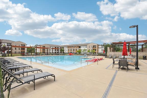 A large outdoor swimming pool with lounge chairs and umbrellas.