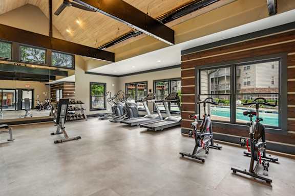 A gym with a row of stationary bikes and a treadmill.