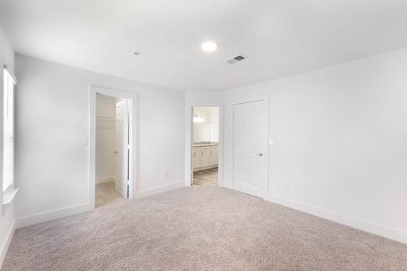 A spacious room with white walls and carpeted floor.