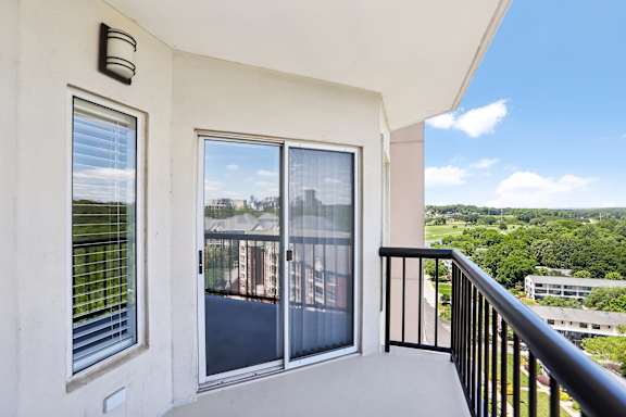A balcony with a view of a parking lot and buildings.