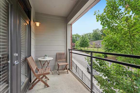 A patio with a table and chairs overlooking a road.