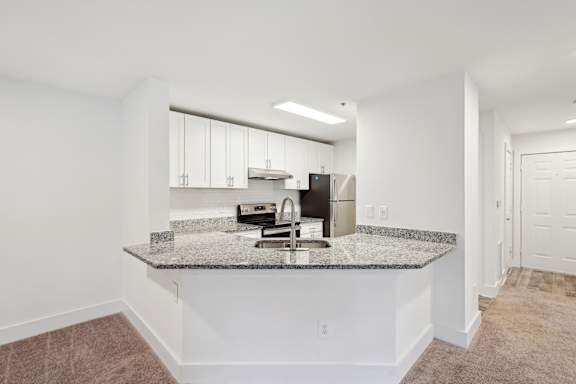 A kitchen with a granite countertop and white cabinets.