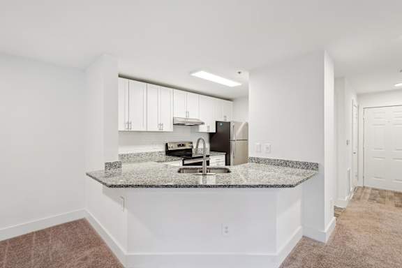 A kitchen with granite countertops and white cabinets.