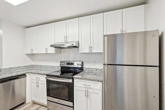 A kitchen with white cabinets and a stainless steel refrigerator.