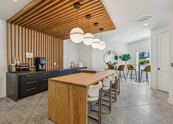 A modern kitchen with a wooden ceiling and a long wooden table.