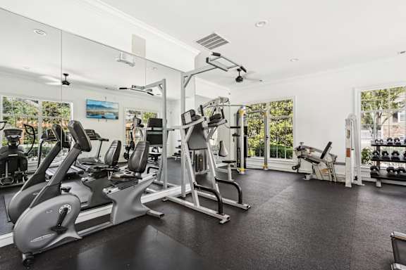 A spacious gym with a variety of equipment including treadmills, stationary bikes, and weight machines.