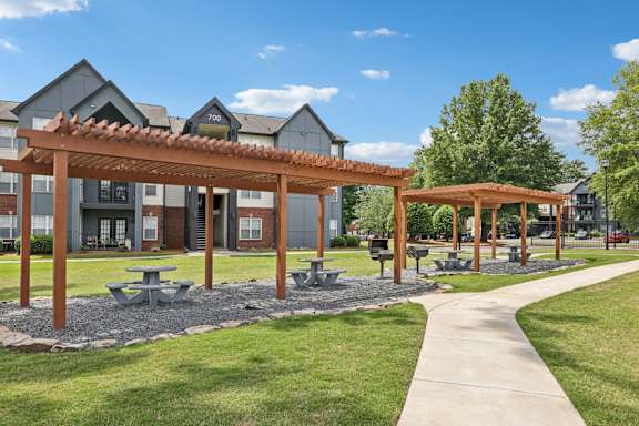 A sunny day at a park with picnic tables and a walking path.