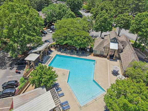 A large swimming pool surrounded by trees and a building.
