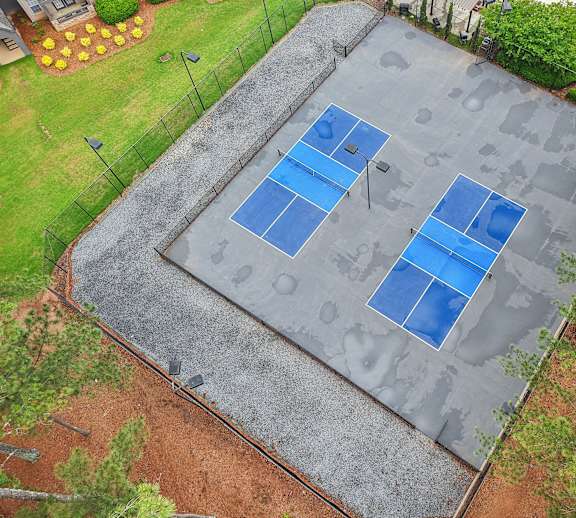 A tennis court with blue and white markings surrounded by a fence.