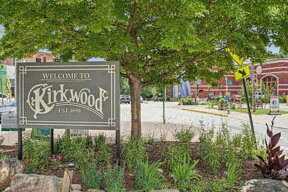 A sign that says "Welcome to Kirkwood" is in front of a tree.