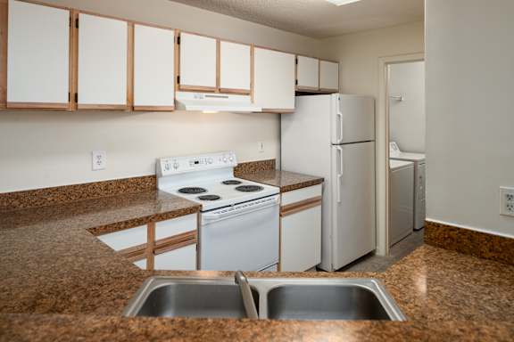 A kitchen with white appliances and brown countertops.