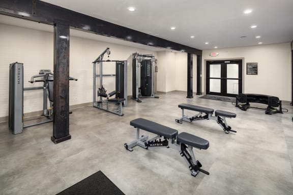 a gym with weights and exercise equipment in a building with white walls
