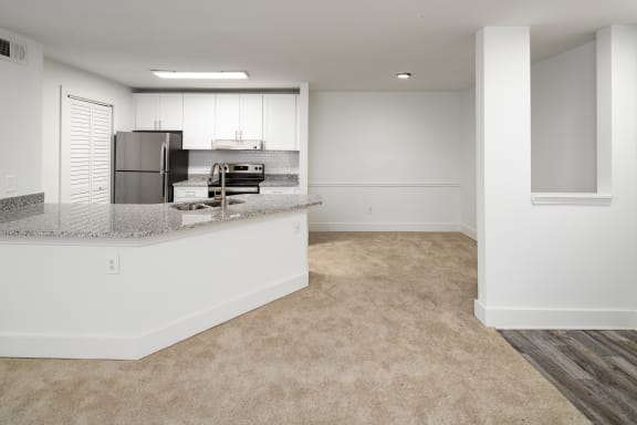 an empty kitchen and living room with a granite counter top