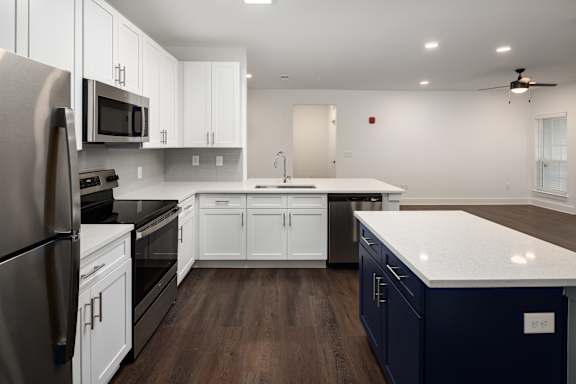 A modern kitchen with dark wood floors and white cabinetry.