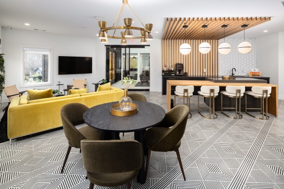 a living room and kitchen with a yellow couch and a table and chairs