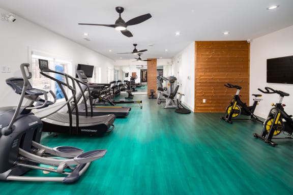 a gym with cardio equipment and weights on a green floor