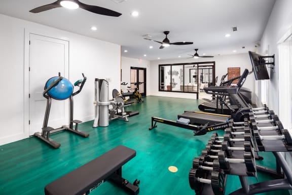 a gym with cardio equipment and weights on a green floor