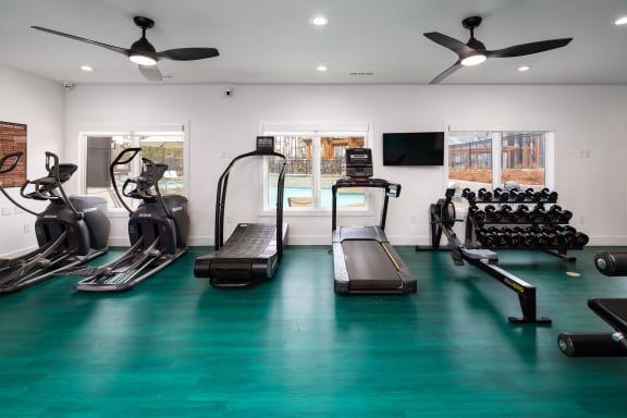 a gym with cardio equipment and weights on a green floor