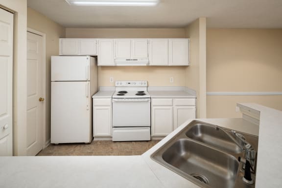 an empty kitchen with white appliances and white cabinets