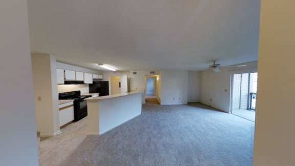 A spacious living room with a kitchen in the background.