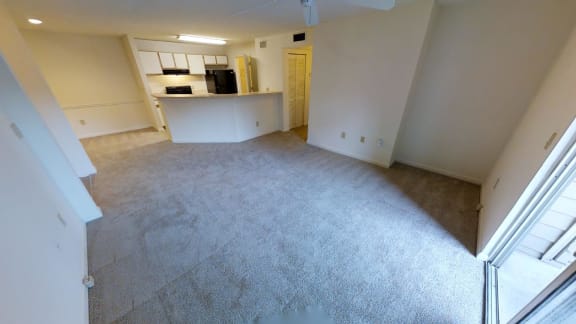 A spacious living room with a kitchen area in the background.