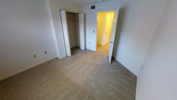 A room with a carpeted floor and two open doors.