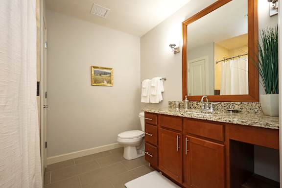 A bathroom with a toilet, sink, and mirror.