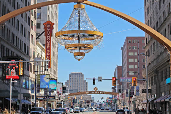 A street view of a busy intersection with a large hanging light fixture.