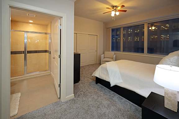 A bedroom with a bed, a ceiling fan, and a window.