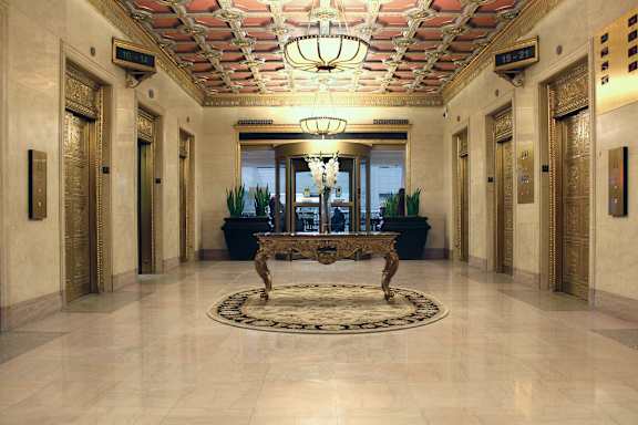 A hallway with a bench and a chandelier.