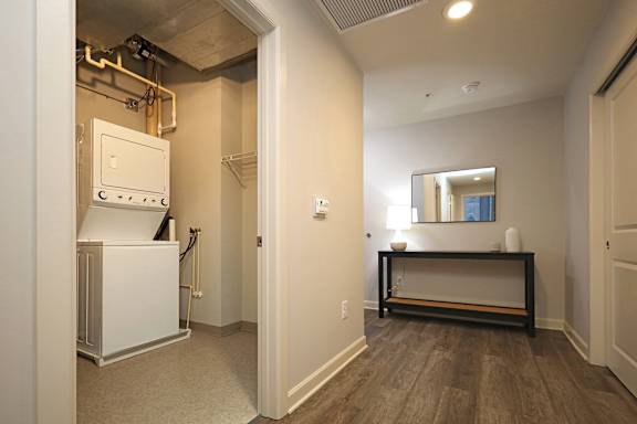 A room with a white fridge and a wooden bench.