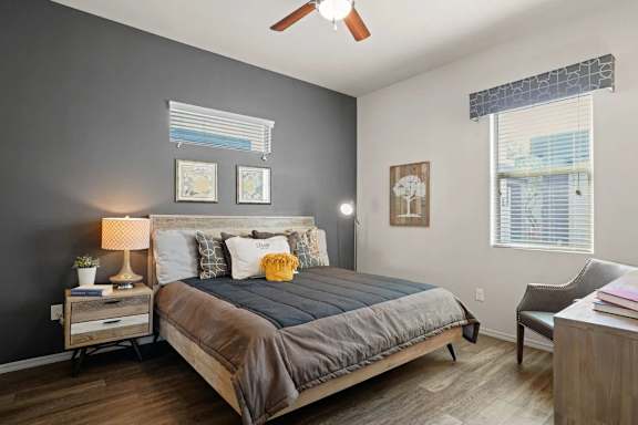 A bedroom with a bed, nightstand, chair, and window.