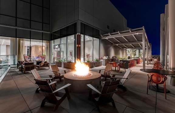 A fire pit sits in the middle of a patio surrounded by chairs.