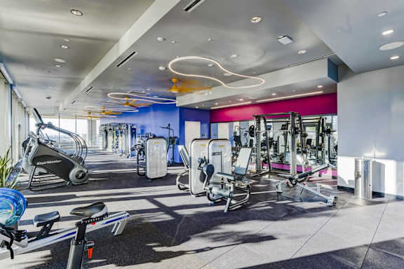 A gym with a variety of equipment including treadmills, stationary bikes, and weight machines.