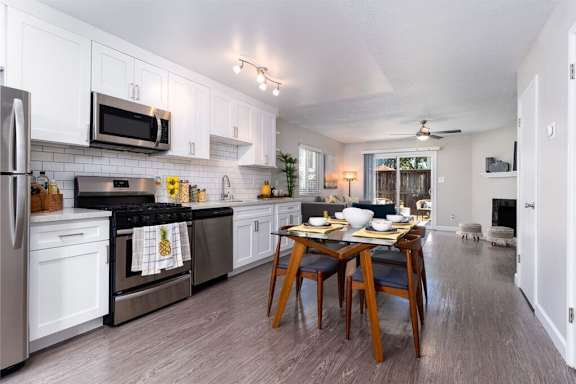 A kitchen with a table set for two with a pineapple towel on the oven door.