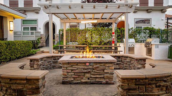 A patio with a fire pit and a pergola.