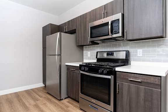 A kitchen with a stainless steel refrigerator, microwave, oven, and stove.