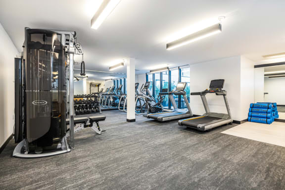 a gym with cardio machines and other exercise equipment at the district flats apartments