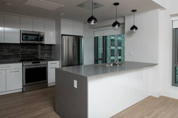 A modern kitchen with a refrigerator, oven, and microwave.