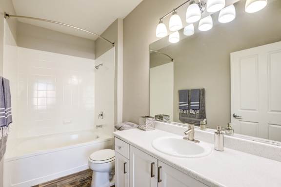 A white bathroom with a toilet, sink, and tub at Avalon at Seven Hills Apartments, Nevada