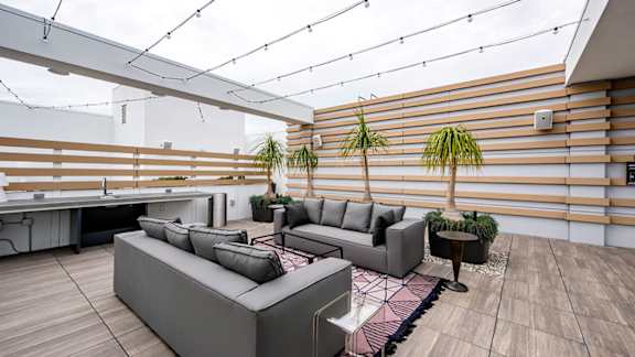 A modern outdoor seating area with grey couches and a wooden floor. at Baker Block, California, 92626