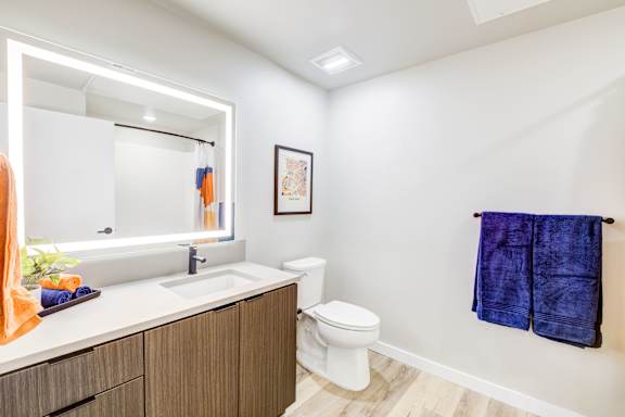 a bathroom with a toilet and an illuminated mirror