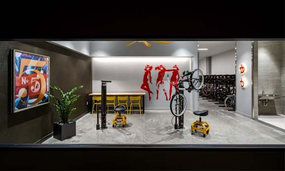 A room with a bicycle, a plant, and a poster on the wall.