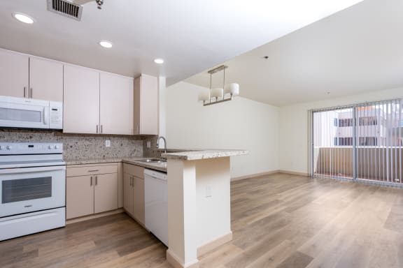an empty kitchen with white cabinets and a counter top