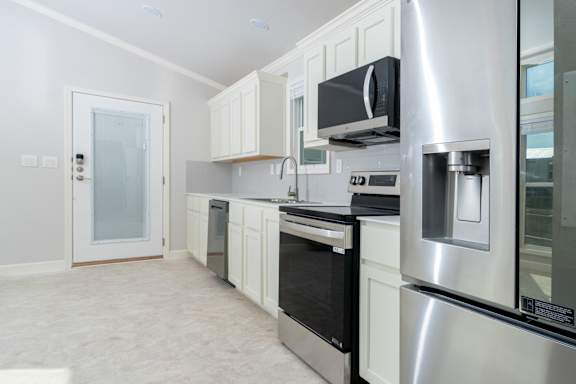 A modern kitchen with stainless steel appliances and white cabinetry.