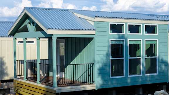 A blue house with a balcony and a metal railing.