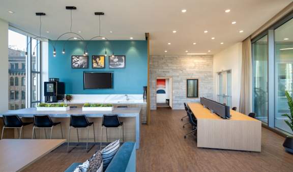 A modern office space with a long table and chairs, a television, and a reception desk.